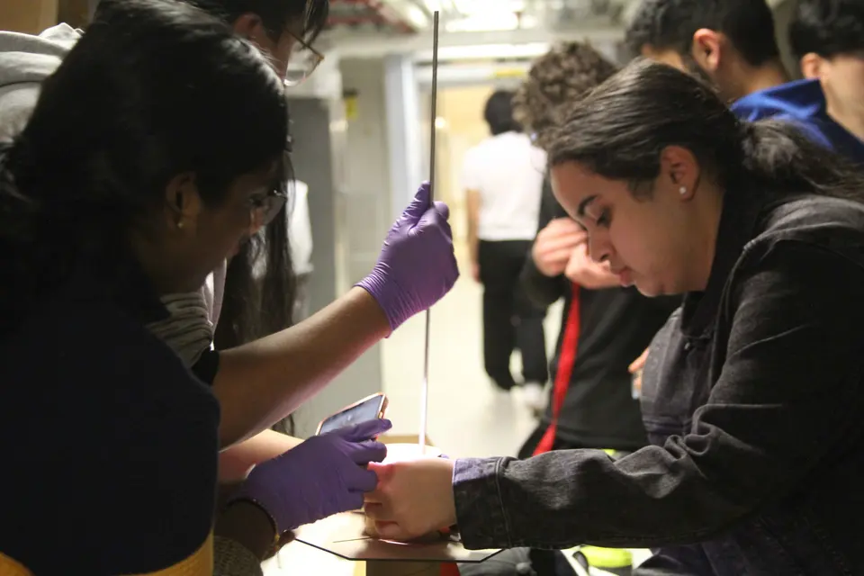 Students wearing gloves assembling a rocket in a workshop