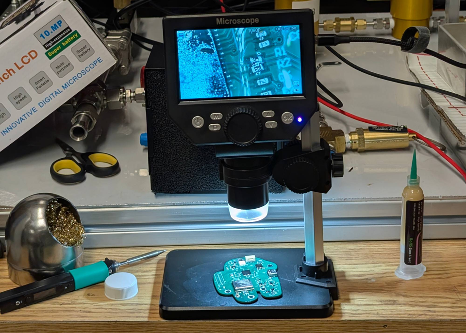 Circuit board beneath a digital microscope on a workbench