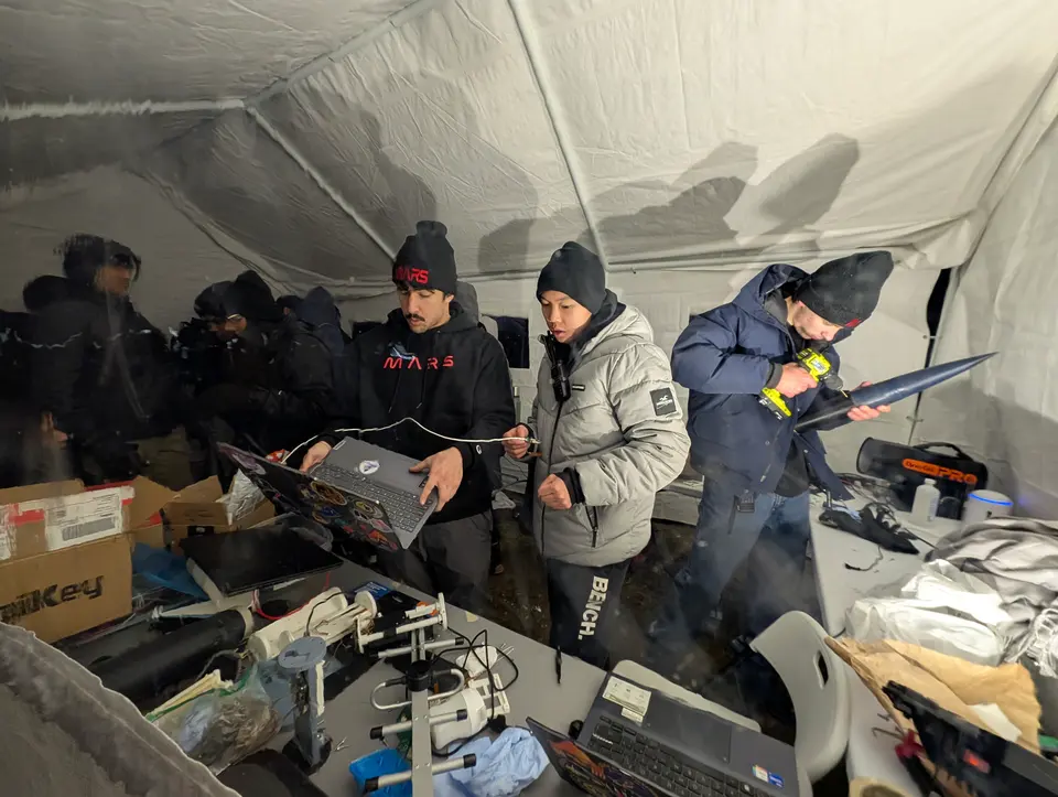 Students preparing equipment inside a field shelter
