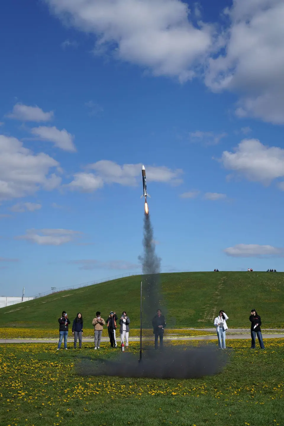 White-nosed rocket climbing on a smoke plume above a grassy hill