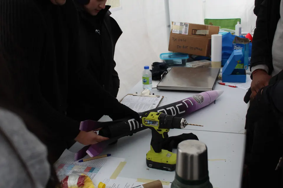 Students working on a rocket at a laboratory bench