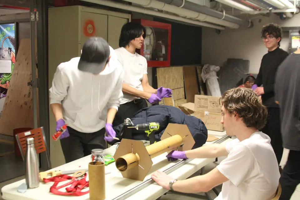 Students assembling rockets together at a workshop table