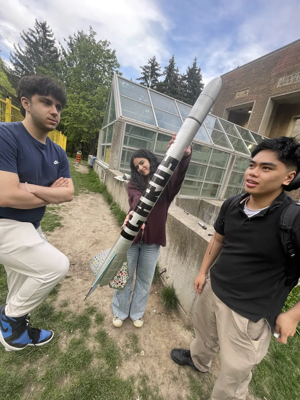 Students carrying a rocket beside a building