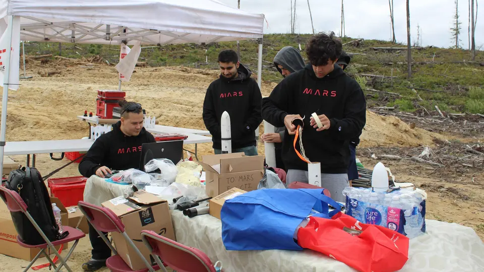 Students preparing equipment at an outdoor canopy table