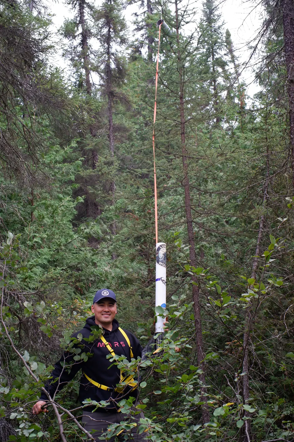 Student holding a tall rocket among trees