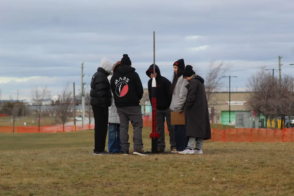 Students standing together beside a launch-field rocket
